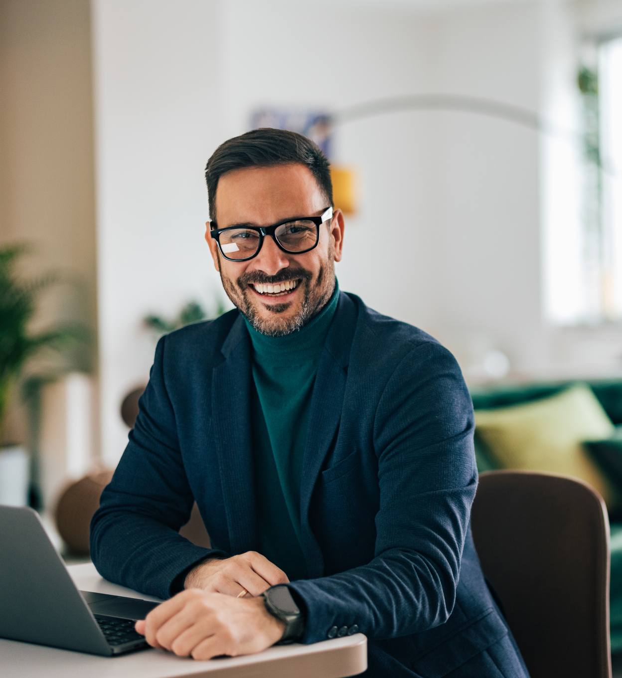 Uśmiechnięty mężczyzna przed kompuetrem ma otwartą stronę internetową akcji w UniCredit. 